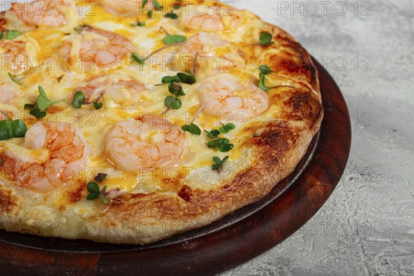 Four cheese pizza with shrimp and fresh microgreens, served on a wooden board, homemade, no people