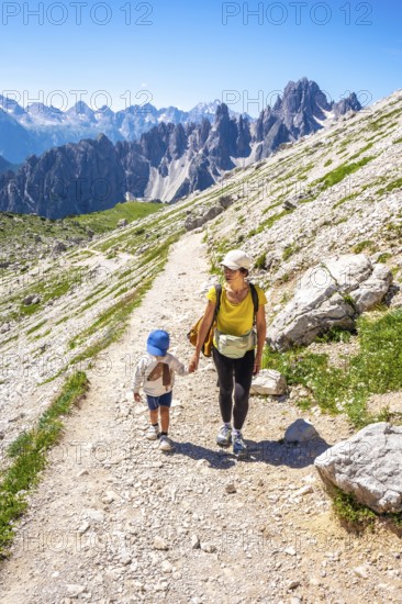 Tourists enjoying a summer hike on a mountain path in the italian alps, with breathtaking views of the tre cime di lavaredo