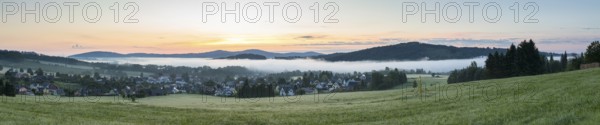 Panorama of the village view with the church of St. Mary's Assumption in the morning fog in front of sunrise, in the background the village church of Crostau, Schirgiswalde, Oberlausitzer Bergland, Saxony, Germany