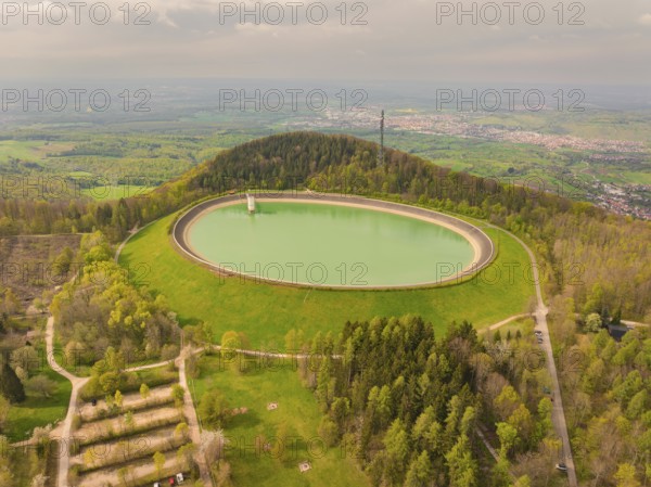 Upper reservoir hill with reservoir and forest, observation tower in the background under cloudy sky, Glems reservoir, Swabian Alb, Germany