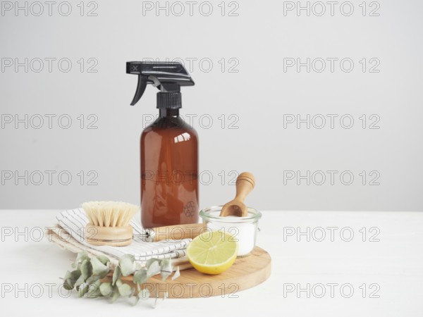 Natural cleaning product in reusable recycled glass bottle. Lemon and baking soda. Natural bristle brush and cotton cloths. Zero waste concept. Plastic free