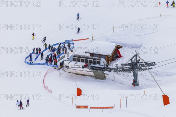 Skiers at the valley station of the chairlift to the summit of Corne de Sorebois, Val d'Anniviers, Valais Alps, Canton Valais, Switzerland