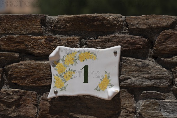 Yellow mimosas and the house number 1 can be seen on a ceramic sign, Bormes les Mimosas, Provence-Alpes-Côte d'Azur, France