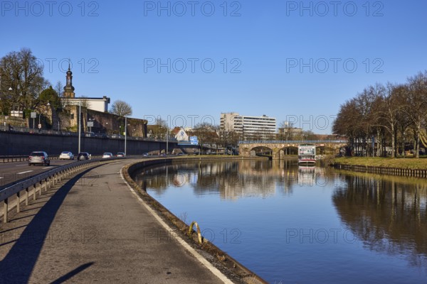 River Saar, footpath and cycle path, river bank, general architecture, church tower, reflections on the water surface, blue sky, cloudless, motorway A620, Old Bridge, Saarbrücken, state capital, regional association Saarbrücken, Saarland, Germany