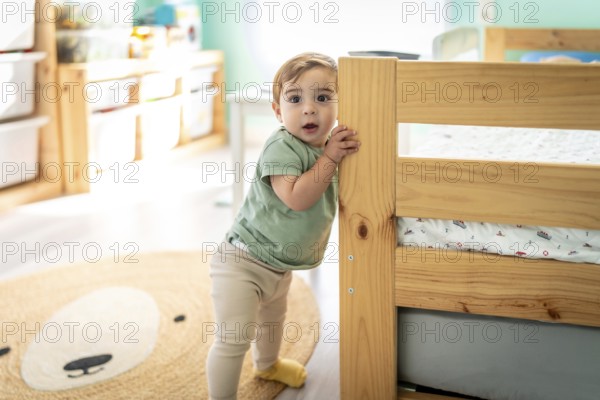 Full length portrait of a male baby taking its first steps in a room