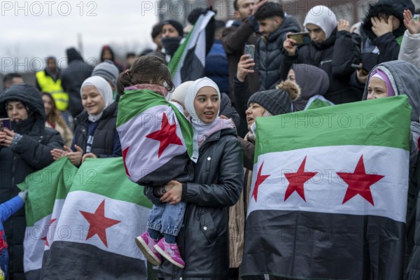 Syrian woman celebrate the end of the Assad regime after the change of power in Syria at a rally on the square in front of the main railway station in Duisburg, North Rhine-Westphalia, Germany