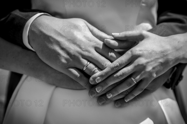 A couple is embracing each other with their hands clasped, and both are wearing wedding rings. Concept of love and commitment between the two individuals