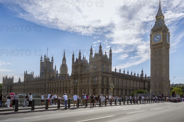 View of Big Ben and the Palace of Westminster with many tourists in the foreground under a partly cloudy sky, London, United Kingdom Great Britain