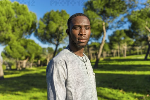 Portrait of a young african man from senegal wearing traditional clothing in a park, representing senegalese culture and muslim traditions