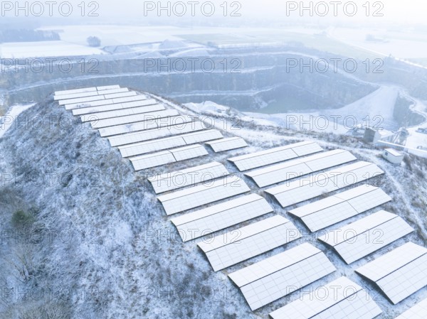 Snow-covered solar panels on hill in winter landscape with light fog, Nagold, Black Forest, Germany
