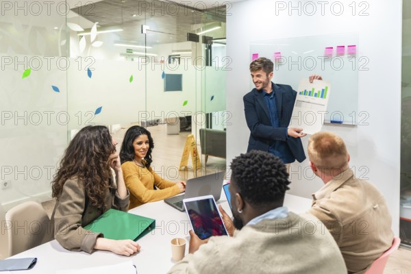 Marketing manager presenting company growth using charts and graphs during a business meeting with his team in a modern office