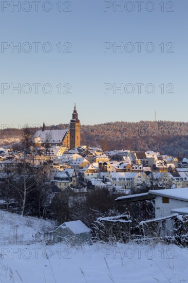 Winter town view with St Wolfgang's Church and Gleesberg in the evening light, Schneeberg in the Ore Mountains, Saxony, Germany