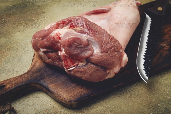Raw pork knuckle, on a wooden chopping board, close-up, top view, no people