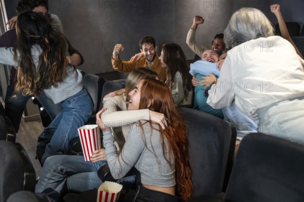 Enthusiastic friends are enjoying a movie at the cinema, hugging, cheering, and sharing a joyful moment together
