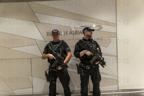 Two armed police officers on duty inside South Terminal, London Gatwick airport, England, UK