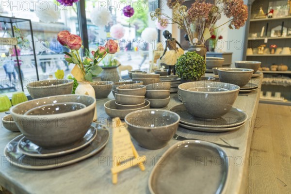 Tableware set in shades of grey on a table surrounded by floral decorations in front of a window, Sindelfingen, Germany