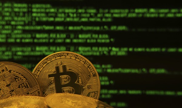 Golden bitcoins in front of green digital code, symbolizing cryptocurrency and technology
