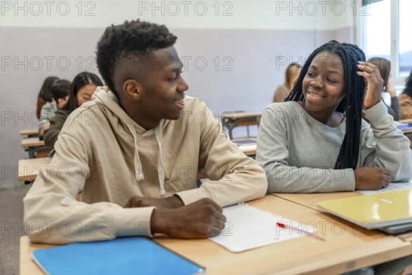 Two college students smiling and engaging in conversation during a lesson, enjoying their time together in a vibrant classroom setting