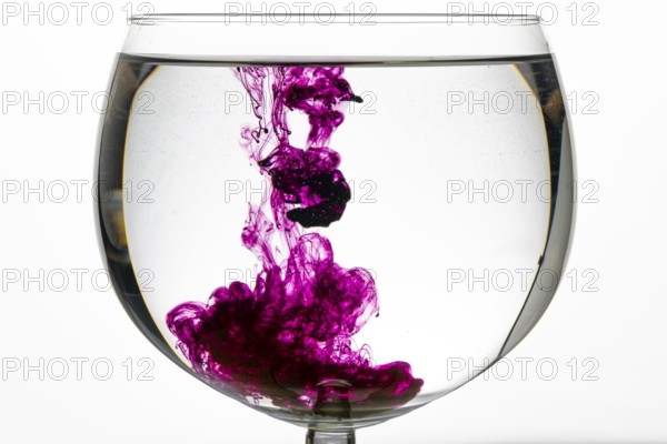 Purple colour unfolds artfully in a glass of water and produces a creative play of colours