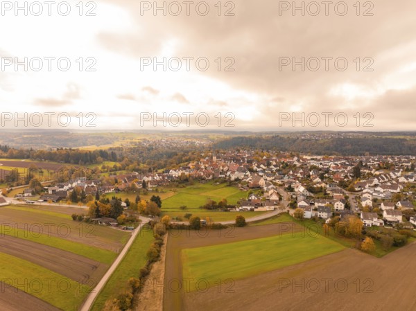 View of a town in an autumnal landscape with clouds in the sky, Tiefenbronn, Germany