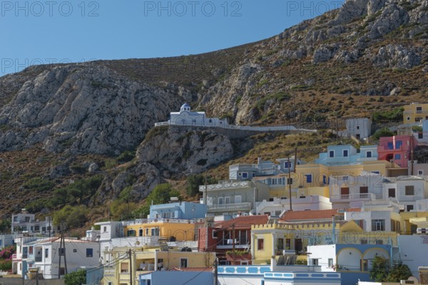 Colourful houses of Menetes with the chapel of Agios Spiridonas on a rock in front of a hill, Menetes, Karpathos, Greece