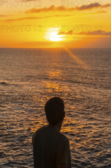 Silhouette of tourist contemplating beautiful golden sunset over atlantic ocean in agaete, gran canaria, canary islands, spain