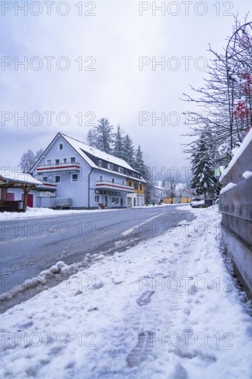 Snow-covered road with building in the background, Enzklösterle, Calw district, Black Forest, Germany