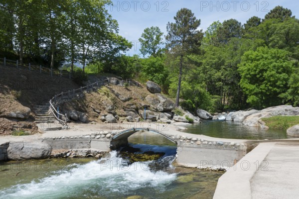 Ein friedlicher Fluss mit einer kleinen Brücke und steinernen Stufen, eingebettet in eine grüne Naturumgebung mit Bäumen und Felsen, Piscinas naturales, natürliche Pools, Schwimmbad, Arenas de San Pedro, Fluss Arenal, Ávila, Avila, Kastilien-León, Kastilien-Leon, Spanien