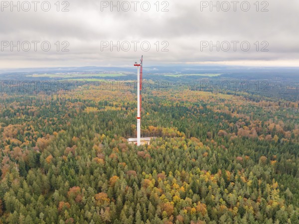 A wind power tower rises above an autumnal forest, shrouded in mist, into a wide landscape, wind farm construction site, Grömbach, Black Forest, Germany