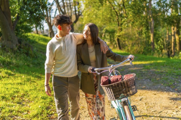 Young couple walking hand in hand through a picturesque park, riding a bicycle and basking in the warm glow of golden hour sunlight