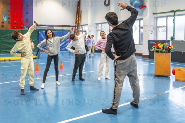 Students and teacher practicing stretching exercises during physical education class in a school gymnasium