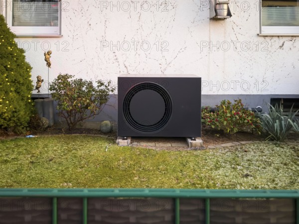 A black heat pump in a front garden in Langenfeld, Germany