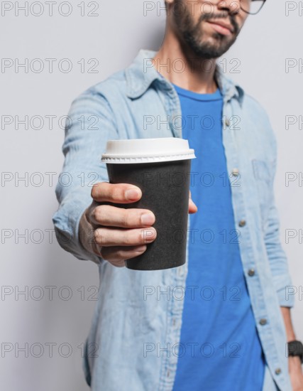 Close up of person offering a coffee to go, Young man offering the camera a coffee to go, Handsome man holding a coffee to go isolated