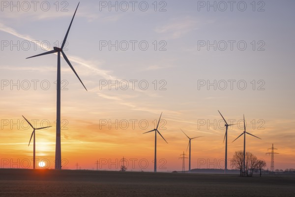 Wind turbines in front of a colourful sunset on the horizon in an open landscape, near Ulm, Swabian Alb, Baden-Württemberg, Germany