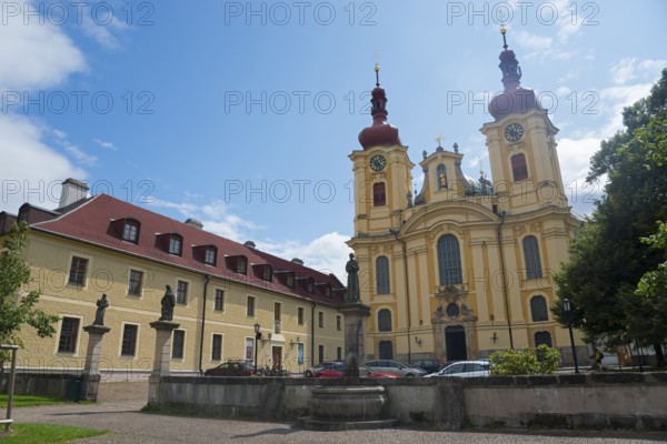 Baroque church next to a building with red roofs and statues, clear blue sky, monastery and pilgrimage church of the Visitation of Mary, Hejnice, Haindorf, Liberec, Czech Republic