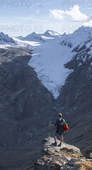 Mountaineer standing on a rock, surrounded by an impressive mountain landscape with snow-covered peaks in autumn View of Gurgler Ferner with summit Hochwilde and Falschungsspitze, Ötztal Alps, Tyrol, Austria