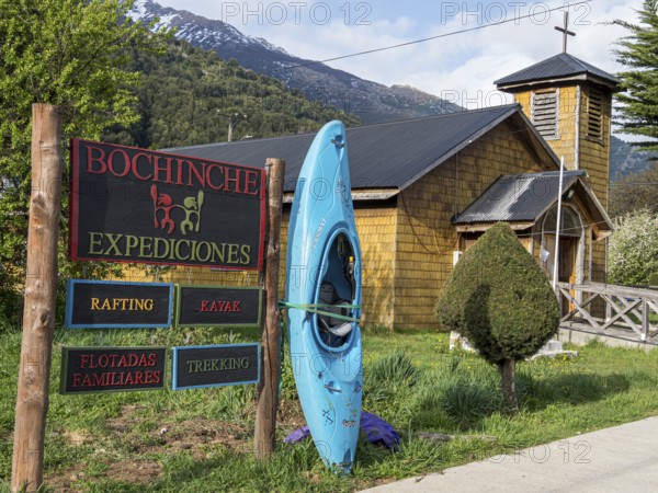 Signpost of tour operator for rafting, kayaking, trekking, next to wooden church, village Futaleufu, Chile
