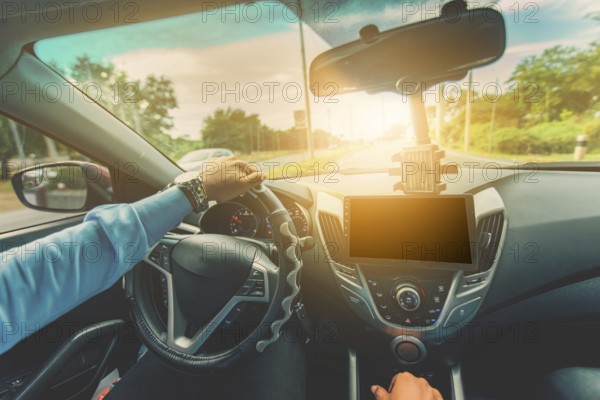 Driver hands on the steering wheel while driving on the asphalt. View of the driver hands driving on the highway
