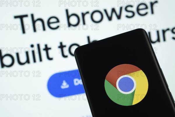 Chrome logo is displayed on a smartphone screen, with the chrome website visible on a computer screen in the background