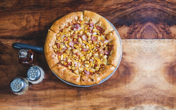 Top view of ham and corn pizza on wooden table. Ham pizza with corn on wooden background