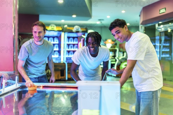Group of young male friends enjoying a game of air hockey in a vibrant entertainment center
