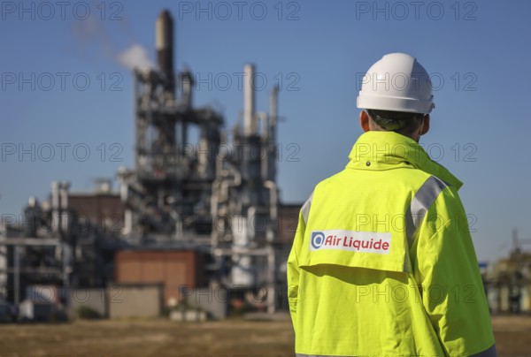 Oberhausen, North Rhine-Westphalia, Germany, Air Liquide, hydrogen production at the OQ Chemicals chemical park. Air Liquid employee with company logo on yellow jacket in front of POX plant (partial oxidation) for the conventional production of hydrogen and synthesis gas. Air Liquide is also planning TRAILBLAZER, a proton exchange membrane (PEM) electrolyser at the Oberhausen site, which produces renewable hydrogen and oxygen from water and renewable electricity