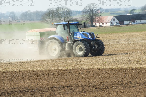 Spring farming, spreading fertilizer with tractor on field in Ystad municipality, Skåne county, Sweden, Scandinavia