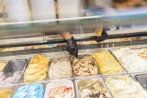 Unrecognizable hands of a worker picking ice cream from counter of a store