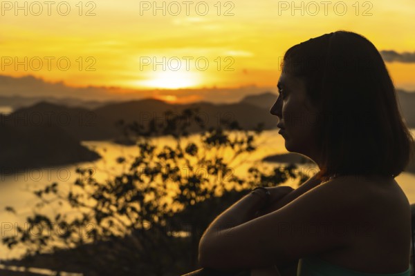 Silhouette of a tourist enjoying a beautiful golden sunset over coron island from mount tapyas viewpoint in busuanga, philippines