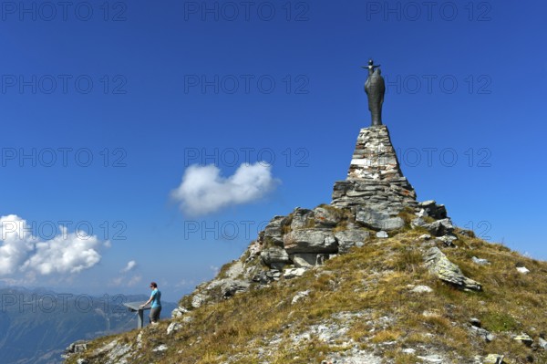 On the summit of Mont Noble, figure of the Virgin Mary with child and hiker at the panorama panel, Nax, municipality of Mont-Noble, Val d'Hérens, Valais, Switzerland