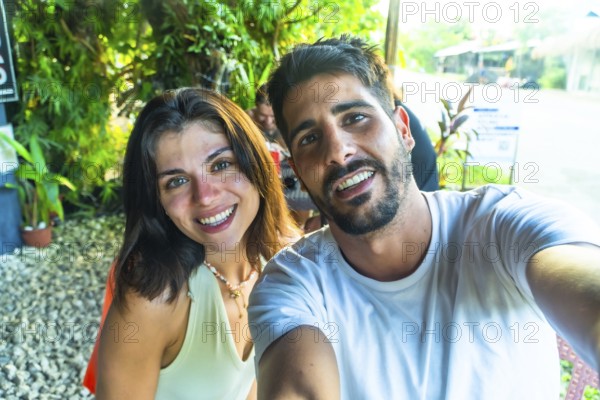 Young couple smiling and taking a selfie during their tropical vacation in siargao island, philippines