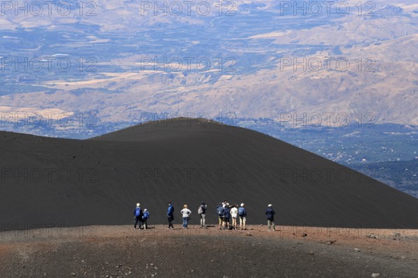 Hikers in the crater landscape of the volcano Etna, summit region, province of Catania, Sicily, Italy