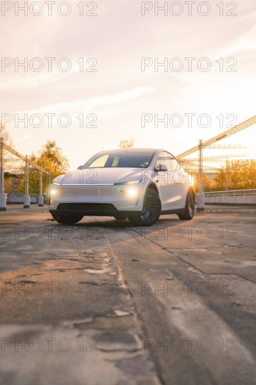 A white car in a city car park in the orange evening light, Tesla new Model Y Juniper, Nagold, Germany