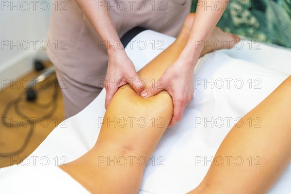 Masseur giving a leg massage at woman lying on the clinic